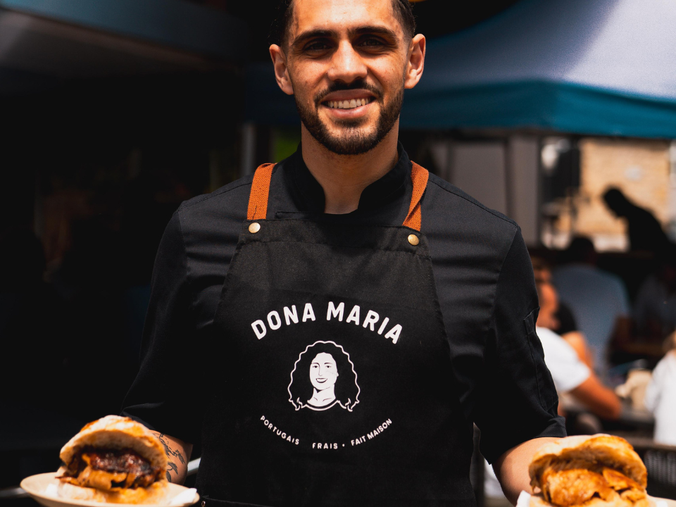 Membre de l’équipe du restaurant Dona Maria présentant deux burgers lors d’un événement à Neuchâtel
