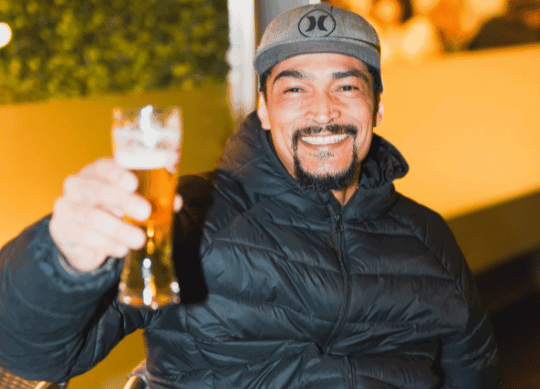 Client assis levant un verre de bière au restaurant Dona Maria à Neuchâtel