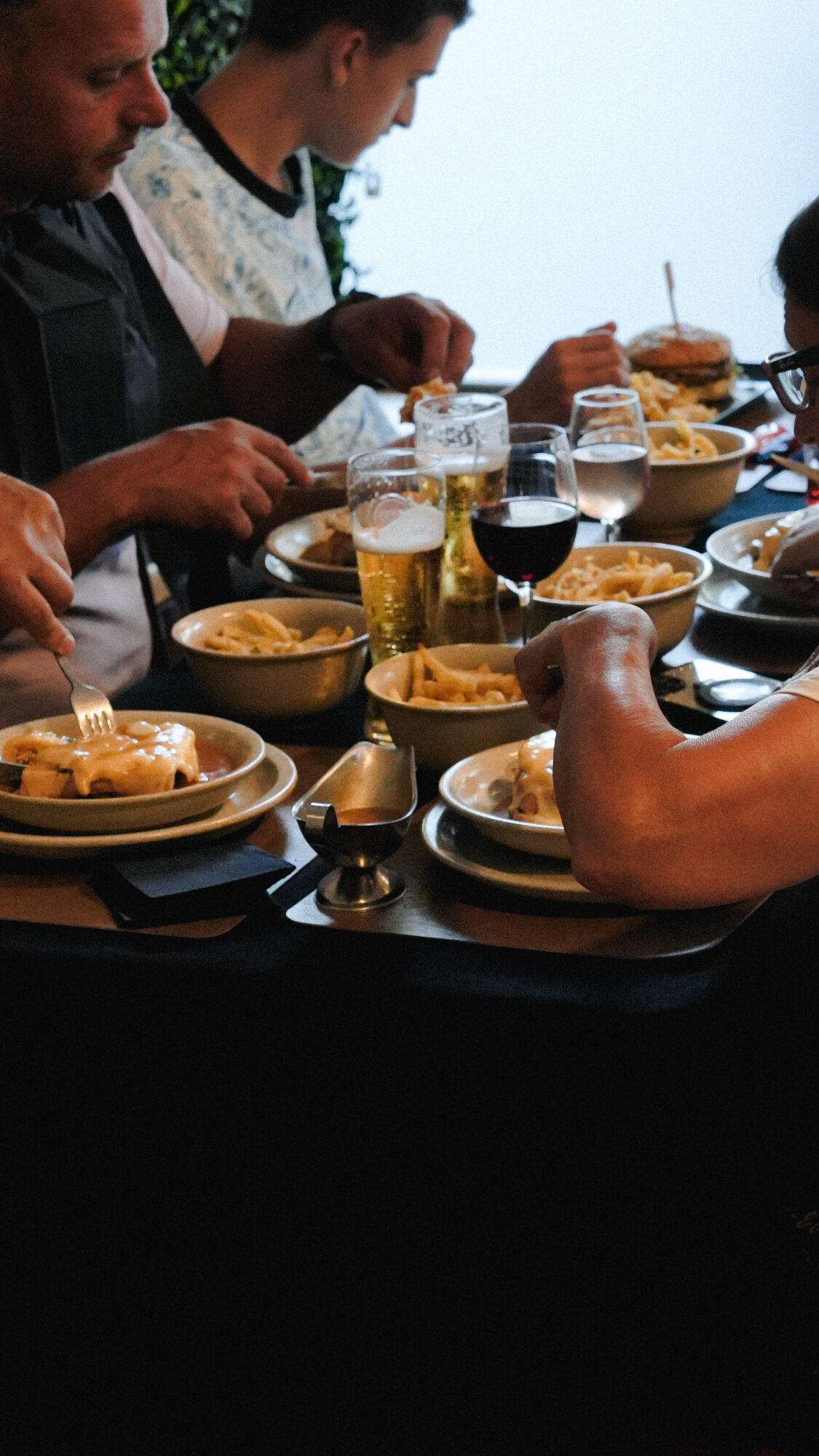 Groupe de clients dégustant une Francesinha avec frites et boissons chez Dona Maria à Neuchâtel