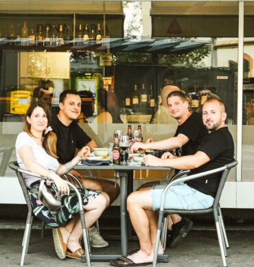 Clients attablés en terrasse devant le restaurant Dona Maria, partageant un repas portugais dans une ambiance conviviale