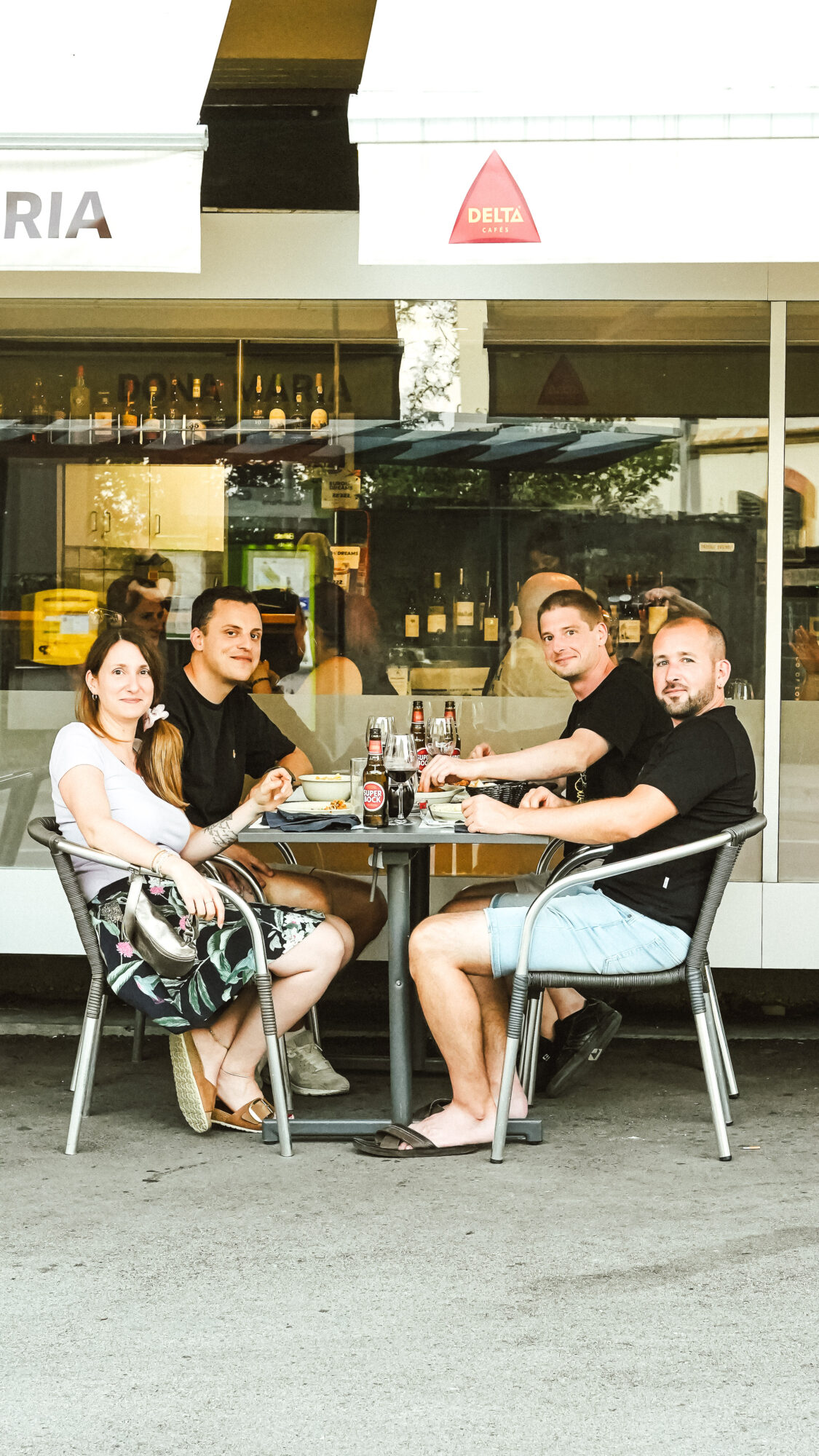 Clients attablés en terrasse devant le restaurant Dona Maria, partageant un repas portugais dans une ambiance conviviale